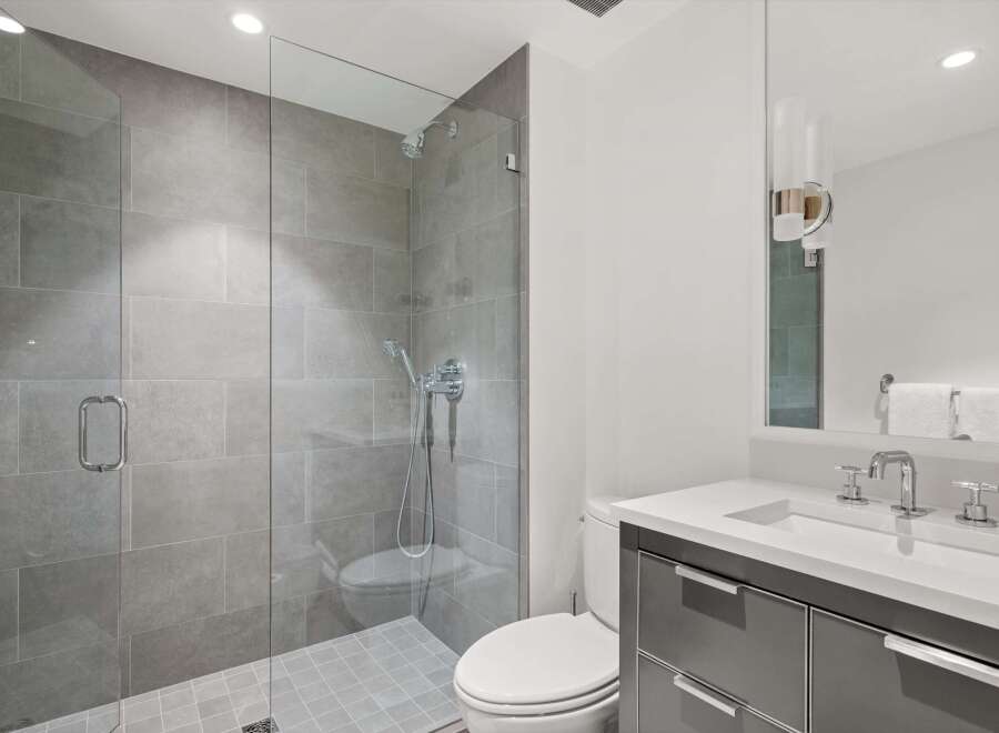 Experience modern luxury in this stunning bathroom featuring a spacious glass-enclosed shower with sleek gray tilework.