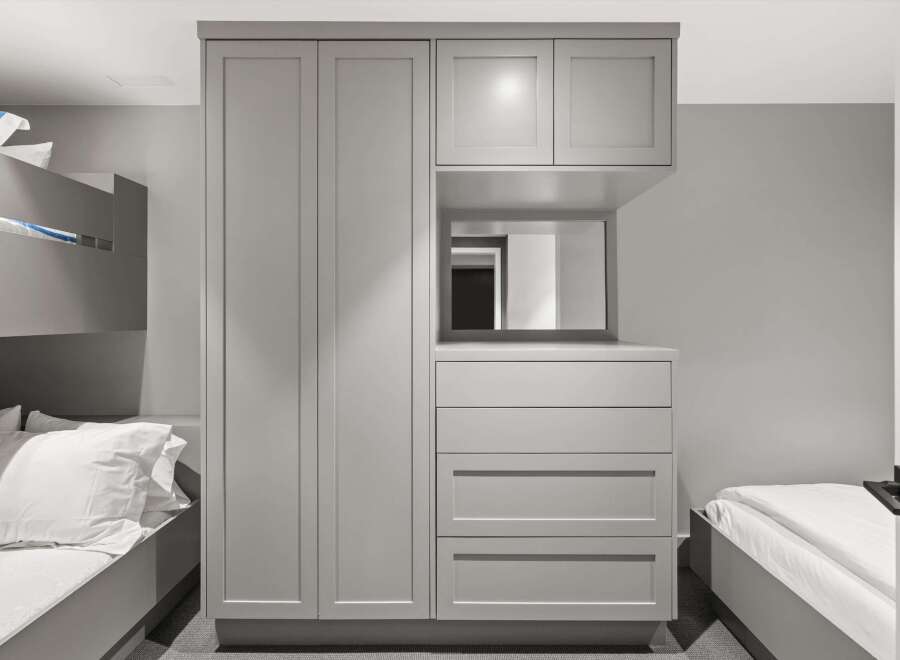 This modern bedroom features a sleek, integrated wardrobe system in a neutral grey tone, offering ample storage solutions.