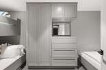 This modern bedroom features a sleek, integrated wardrobe system in a neutral grey tone, offering ample storage solutions.