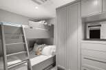 This modern bedroom features a space-saving bunk bed with a ladder, perfect for children's rooms or guest accommodations.
