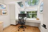 This home office features a sleek white built-in desk with ample storage, complemented by a modern black mesh office chair.