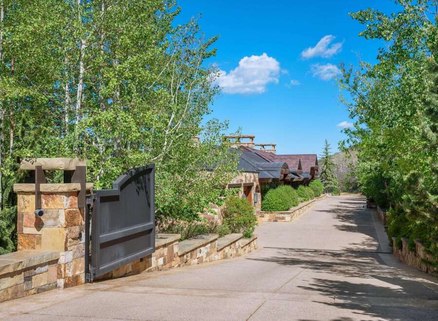 Discover this stunning mountain estate, accessed via a grand stone gate and a winding driveway lined with mature trees.