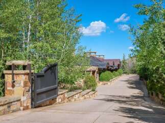 Discover this stunning mountain estate, accessed via a grand stone gate and a winding driveway lined with mature trees.