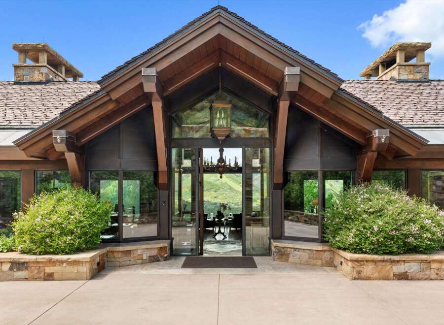 Experience breathtaking mountain views from this stunning entryway, featuring expansive glass walls and a grand chandelier.