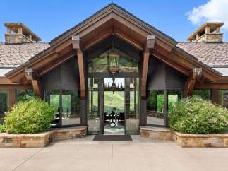 Experience breathtaking mountain views from this stunning entryway, featuring expansive glass walls and a grand chandelier.