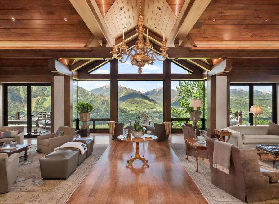 Experience luxury mountain living in this stunning great room, featuring a soaring wood-beamed ceiling and a magnificent gold chandelier.