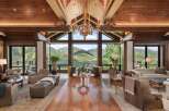 Experience luxury mountain living in this stunning great room, featuring a soaring wood-beamed ceiling and a magnificent gold chandelier.