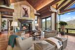 Experience luxury mountain living in this stunning great room, featuring a grand stone fireplace and vaulted wood-beamed ceilings.