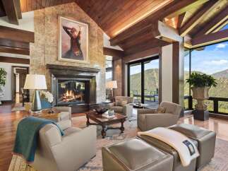 Experience luxury mountain living in this stunning great room, featuring a grand stone fireplace and vaulted wood-beamed ceilings.