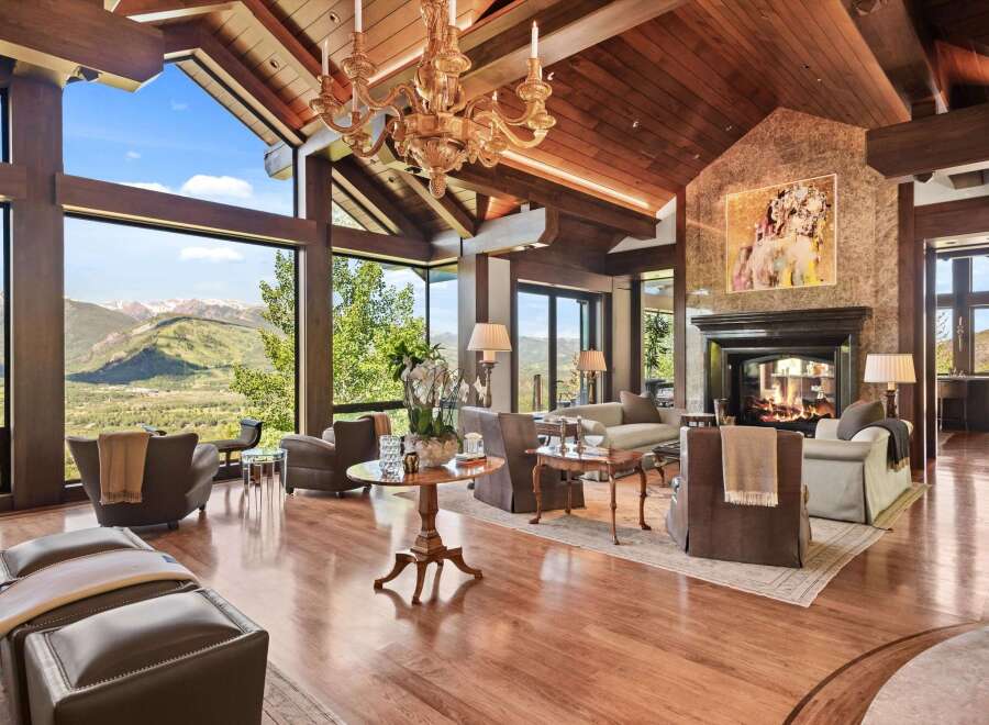Experience luxury mountain living in this stunning great room, featuring soaring vaulted ceilings with exposed wooden beams and a magnificent stone fireplace.