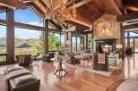 Experience luxury mountain living in this stunning great room, featuring soaring vaulted ceilings with exposed wooden beams and a magnificent stone fireplace.