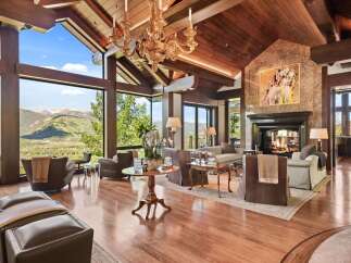 Experience luxury mountain living in this stunning great room, featuring soaring vaulted ceilings with exposed wooden beams and a magnificent stone fireplace.
