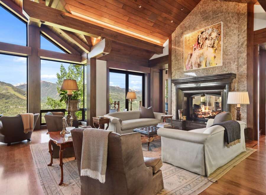 Experience luxurious mountain living in this stunning great room, featuring a grand stone fireplace and soaring vaulted ceilings with exposed wooden beams.