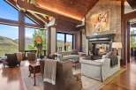 Experience luxurious mountain living in this stunning great room, featuring a grand stone fireplace and soaring vaulted ceilings with exposed wooden beams.