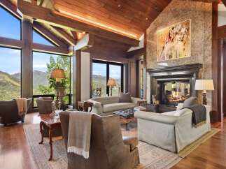 Experience luxurious mountain living in this stunning great room, featuring a grand stone fireplace and soaring vaulted ceilings with exposed wooden beams.