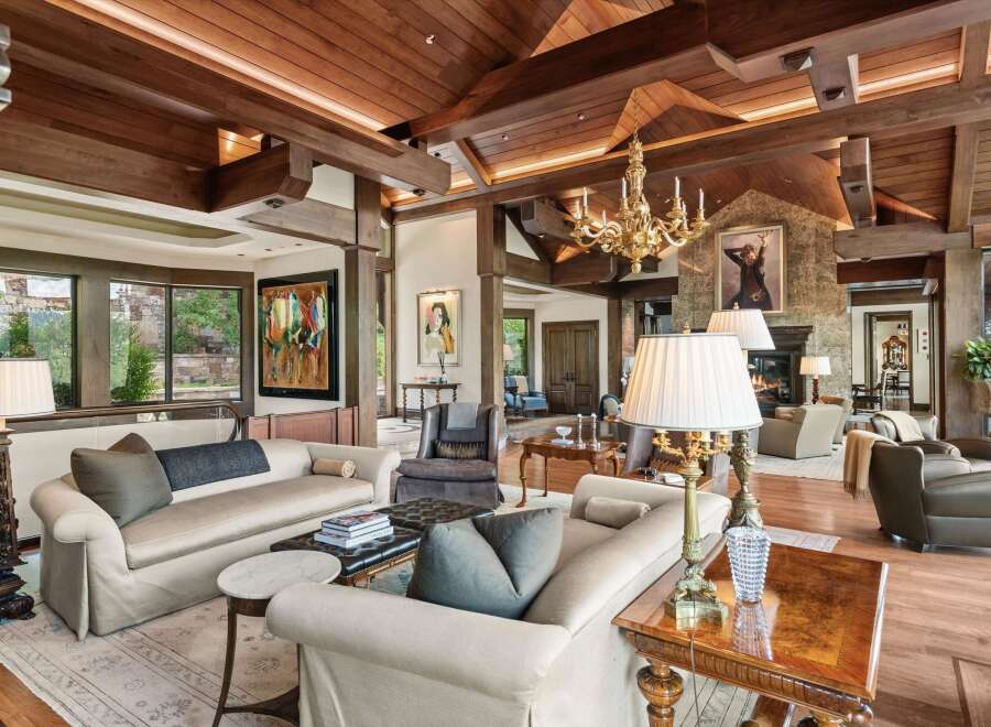Experience luxurious living in this grand living room, featuring a soaring wood-beamed ceiling and a magnificent gold chandelier.