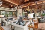 Experience luxurious living in this grand living room, featuring a soaring wood-beamed ceiling and a magnificent gold chandelier.