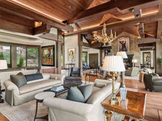 Experience luxurious living in this grand living room, featuring a soaring wood-beamed ceiling and a magnificent gold chandelier.