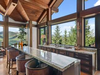 Experience breathtaking mountain views from this stunning bar area, featuring a granite countertop and comfortable seating.