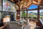 Experience breathtaking mountain views from this luxurious living room, featuring a grand fireplace and a stunning chandelier.