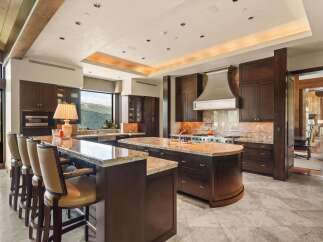 Experience luxury living in this stunning gourmet kitchen, featuring custom dark wood cabinetry, granite countertops, and a large island perfect for entertaining.