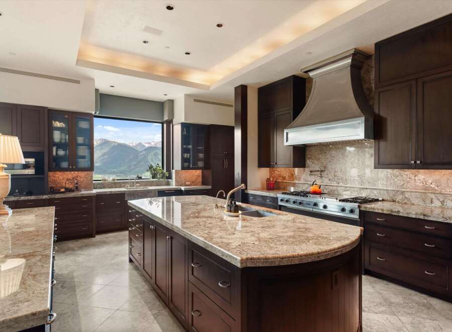 Experience luxury in this expansive kitchen featuring rich, dark wood cabinetry and gleaming granite countertops.