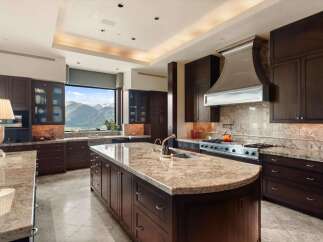 Experience luxury in this expansive kitchen featuring rich, dark wood cabinetry and gleaming granite countertops.