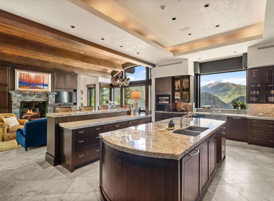 Experience luxury living in this stunning mountain-view kitchen, featuring rich dark wood cabinetry, expansive granite countertops, and a large island with a double sink.