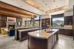 Experience luxury living in this stunning mountain-view kitchen, featuring rich dark wood cabinetry, expansive granite countertops, and a large island with a double sink.
