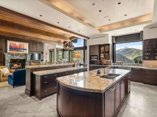 Experience luxury living in this stunning mountain-view kitchen, featuring rich dark wood cabinetry, expansive granite countertops, and a large island with a double sink.