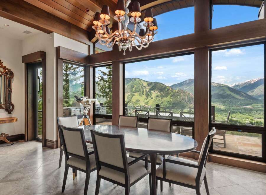 Experience breathtaking mountain views from this elegant dining room, featuring a large oval table and plush seating perfect for hosting.