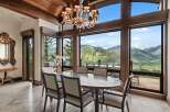 Experience breathtaking mountain views from this elegant dining room, featuring a large oval table and plush seating perfect for hosting.