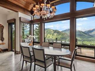 Experience breathtaking mountain views from this elegant dining room, featuring a large oval table and plush seating perfect for hosting.