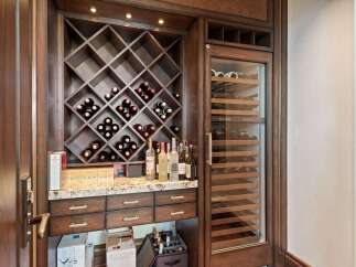 Indulge in the ultimate entertaining experience with this custom-built wine cellar, featuring a diamond-patterned wine rack and a state-of-the-art wine refrigerator.