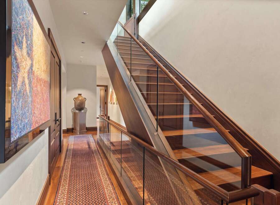Experience luxury living with this stunning staircase featuring rich wood treads and a sleek glass railing.