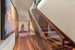 Experience luxury living with this stunning staircase featuring rich wood treads and a sleek glass railing.