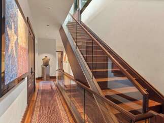 Experience luxury living with this stunning staircase featuring rich wood treads and a sleek glass railing.