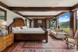 Experience luxury mountain living in this exquisite bedroom featuring a grand wooden bed and a cozy fireplace.