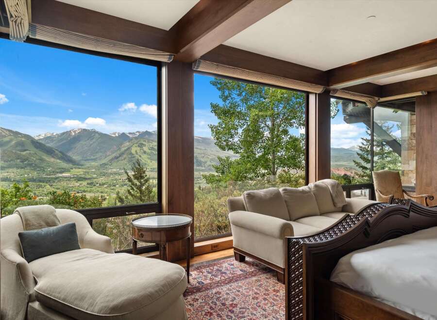 Experience breathtaking mountain views from this luxurious bedroom, featuring expansive windows that frame a stunning landscape.