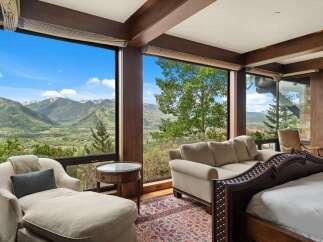 Experience breathtaking mountain views from this luxurious bedroom, featuring expansive windows that frame a stunning landscape.