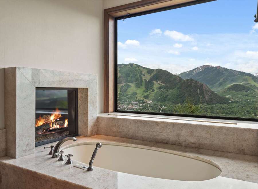 Indulge in ultimate relaxation with this luxurious bathroom featuring a stunning marble fireplace and a deep soaking tub.