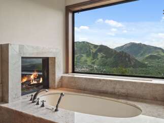 Indulge in ultimate relaxation with this luxurious bathroom featuring a stunning marble fireplace and a deep soaking tub.