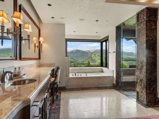 Indulge in luxury with this stunning bathroom featuring a spacious soaking tub with breathtaking mountain views.