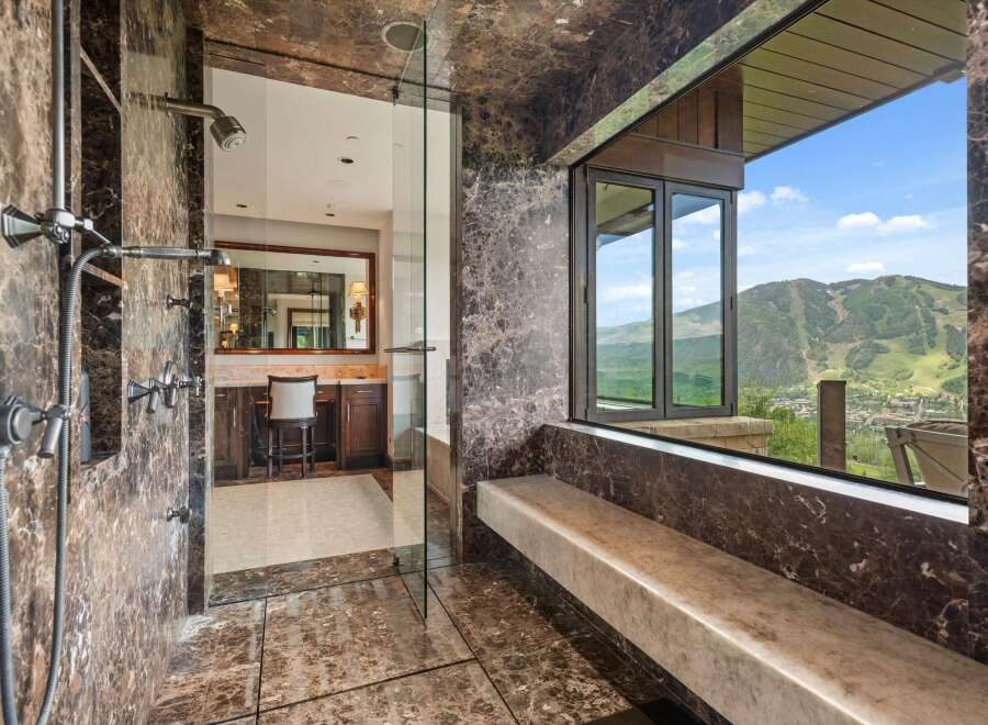Experience unparalleled luxury in this master bathroom featuring a spacious marble shower with multiple shower heads and a stunning view of the surrounding mountains.