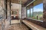 Experience unparalleled luxury in this master bathroom featuring a spacious marble shower with multiple shower heads and a stunning view of the surrounding mountains.