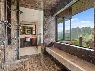 Experience unparalleled luxury in this master bathroom featuring a spacious marble shower with multiple shower heads and a stunning view of the surrounding mountains.
