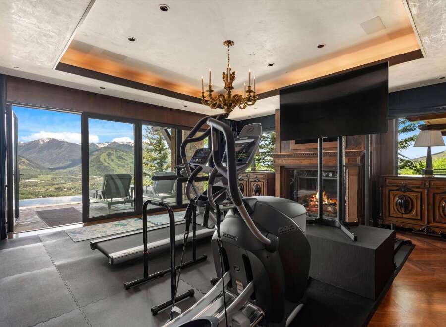 Experience luxury fitness with this state-of-the-art home gym, featuring a treadmill and elliptical with breathtaking mountain views.