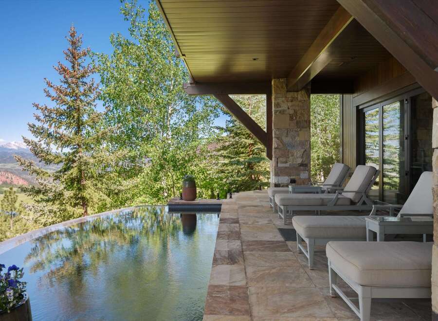 Experience luxury outdoor living with this stunning infinity pool overlooking a picturesque mountain landscape.