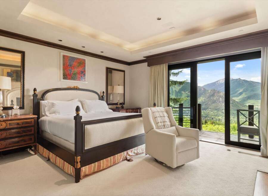 Experience luxury mountain living in this exquisite bedroom, featuring a plush king-size bed and a comfortable recliner perfect for enjoying the breathtaking panoramic views.