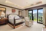 Experience luxury mountain living in this exquisite bedroom, featuring a plush king-size bed and a comfortable recliner perfect for enjoying the breathtaking panoramic views.